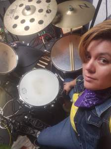 Angie at their drumset, Links to their teaching profile on TakeLessons.com.